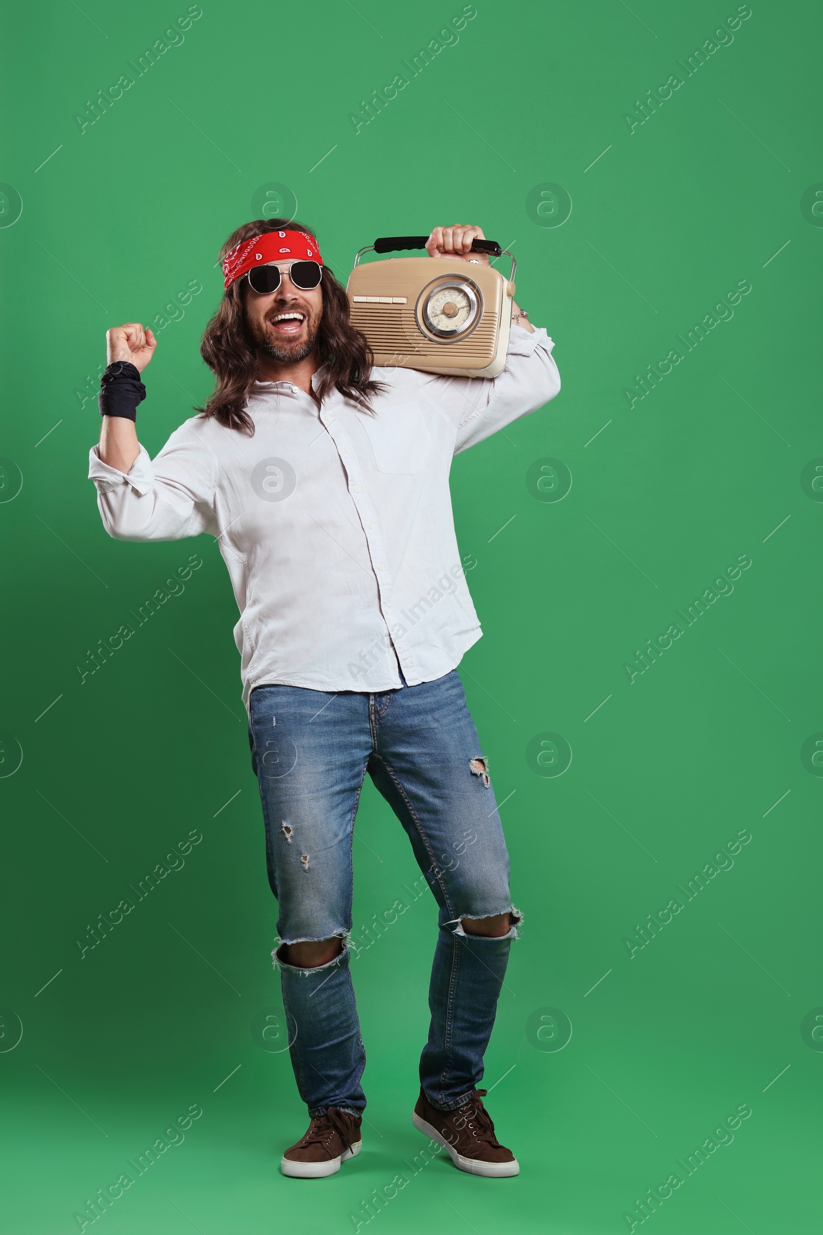 Photo of Stylish hippie man in sunglasses with retro radio receiver on green background