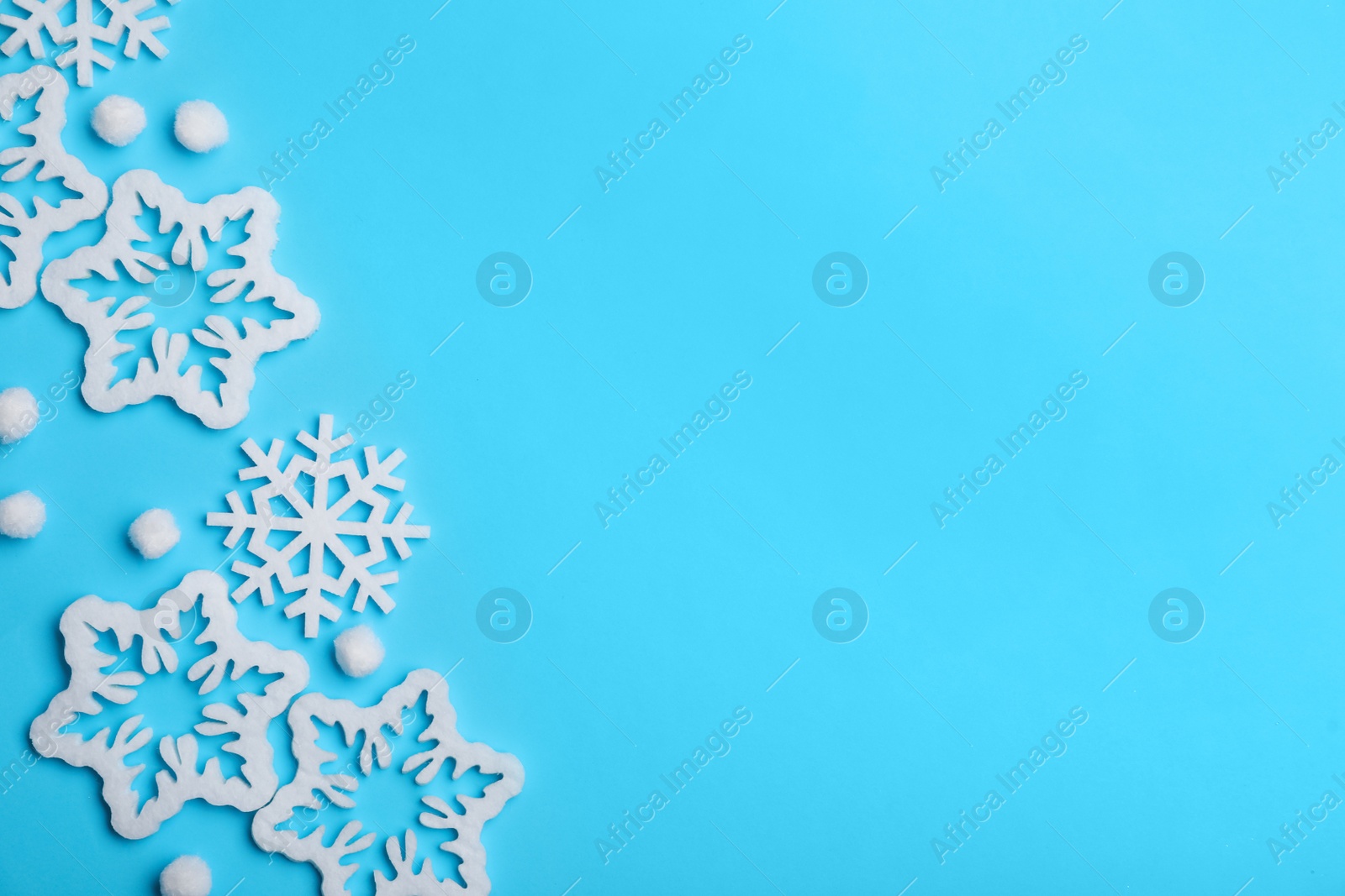 Photo of Beautiful decorative snowflakes on light blue background, flat lay. Space for text