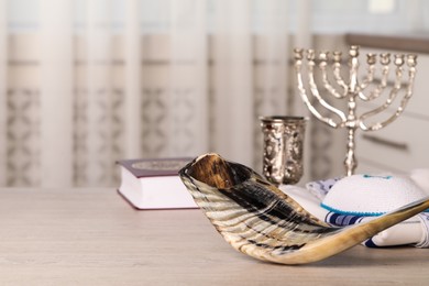 Photo of Shofar and other Rosh Hashanah holiday attributes on wooden table indoors, space for text.