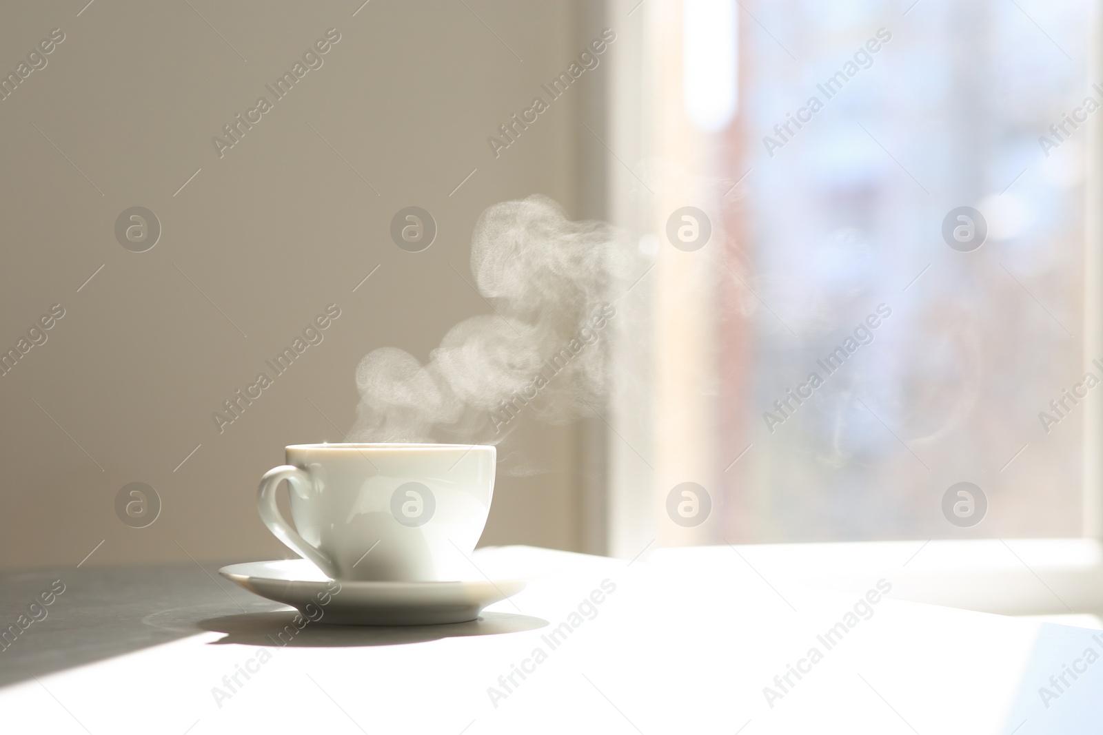 Photo of Cup of delicious coffee on sunlit table, space for text. Good morning