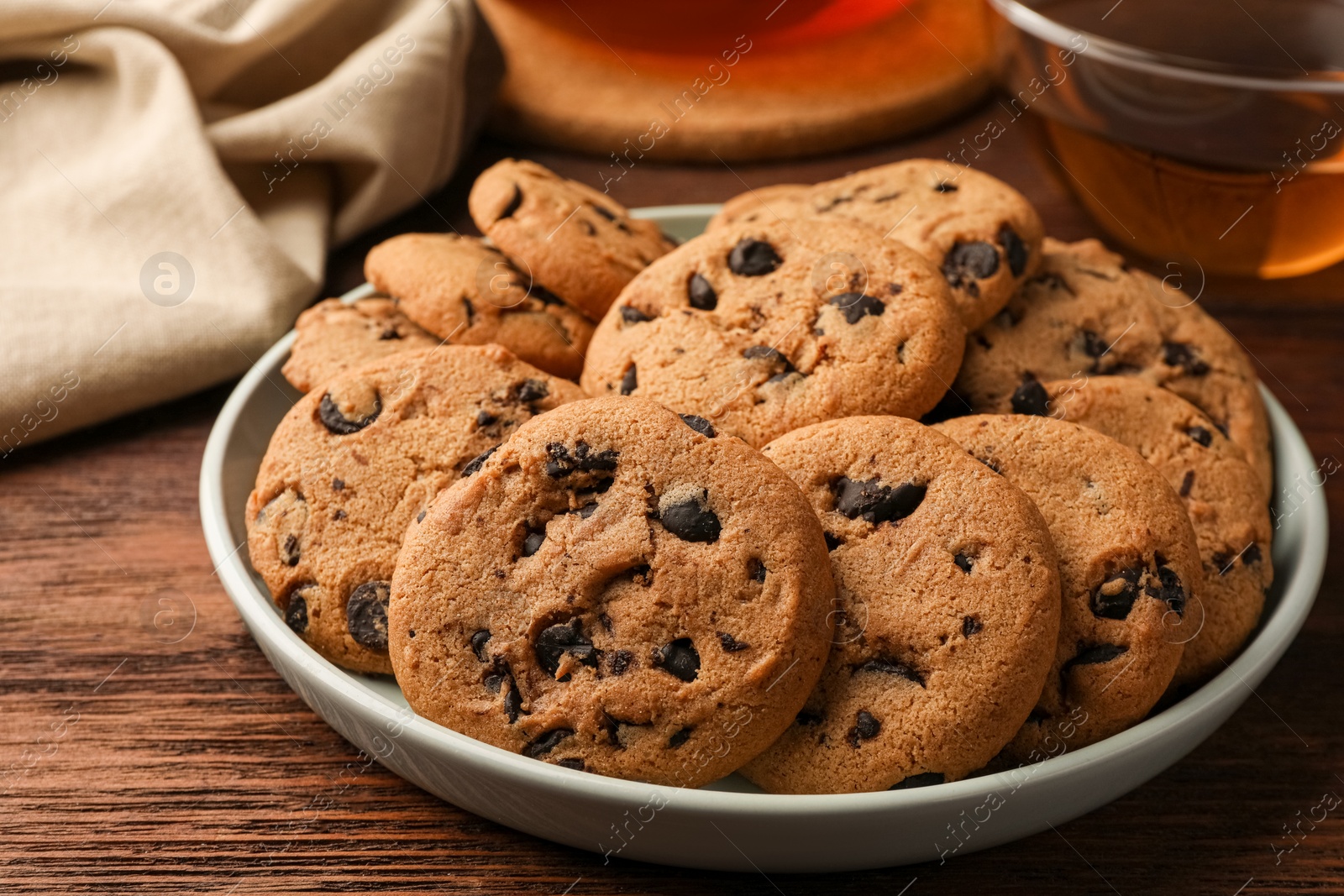 Photo of Delicious chocolate chip cookies and tea on wooden table, closeup