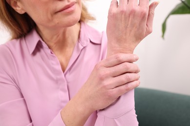 Woman suffering from pain in elbow indoors, closeup. Arthritis symptoms
