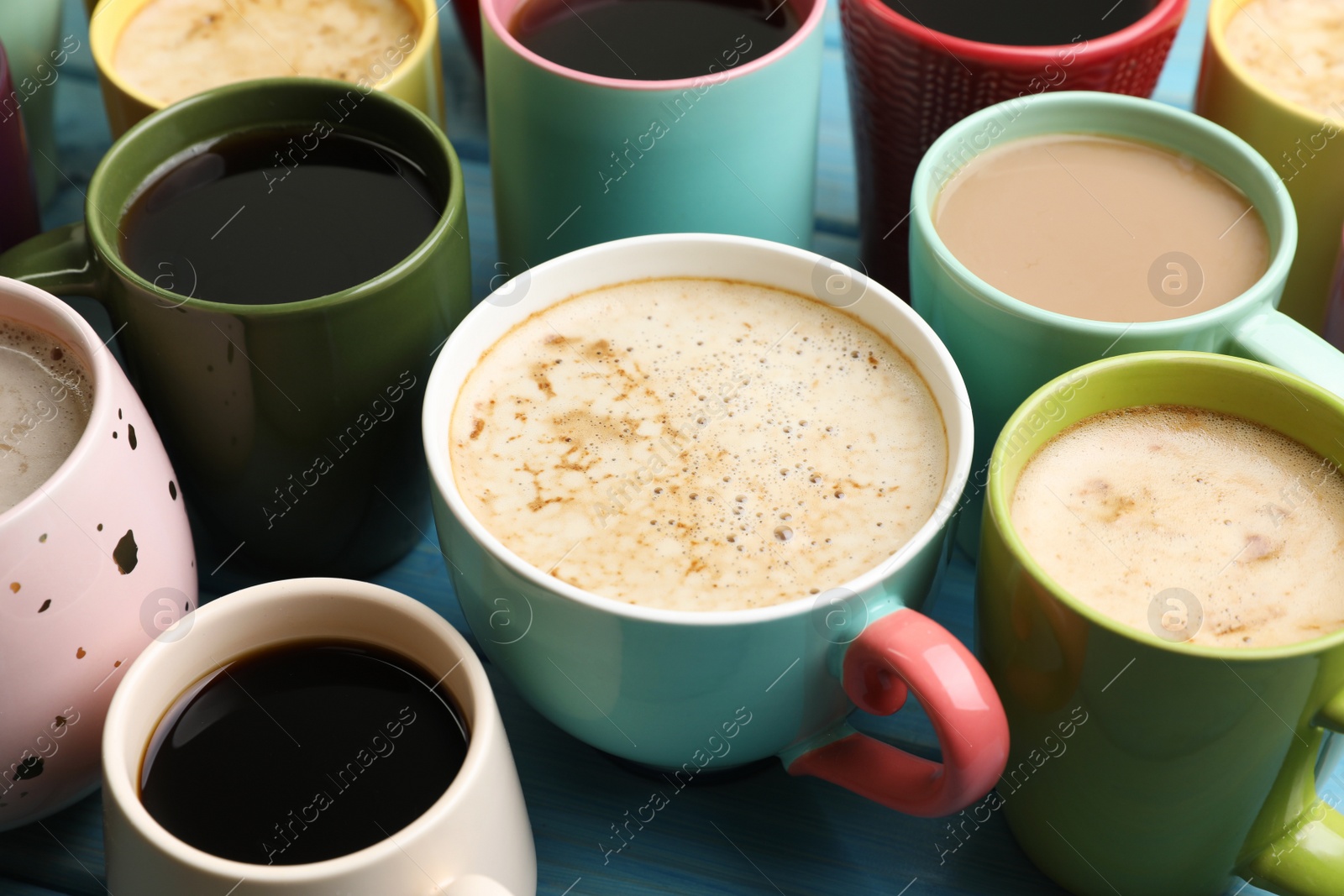Photo of Many cups of different coffee drinks on light blue table