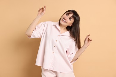 Photo of Happy woman wearing pyjama on beige background
