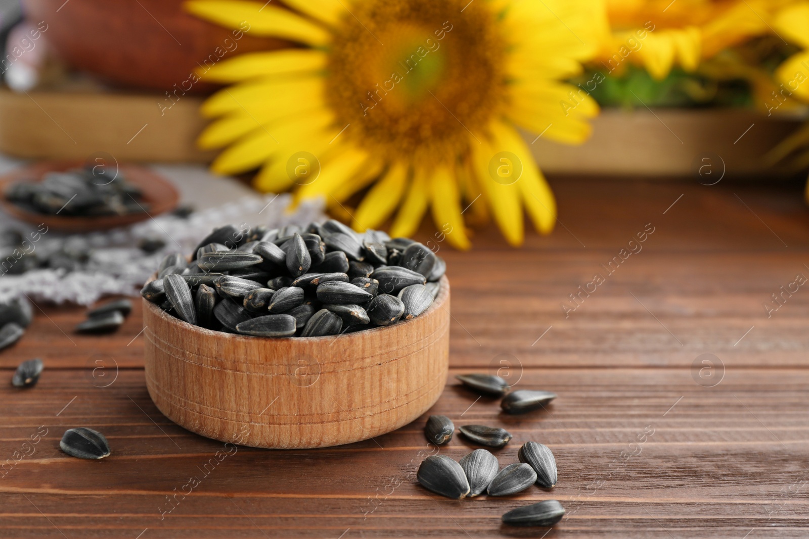 Photo of Bowl with sunflower seeds on wooden table, closeup