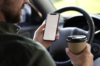 Coffee to go. Man with paper cup of drink and smartphone in car, closeup