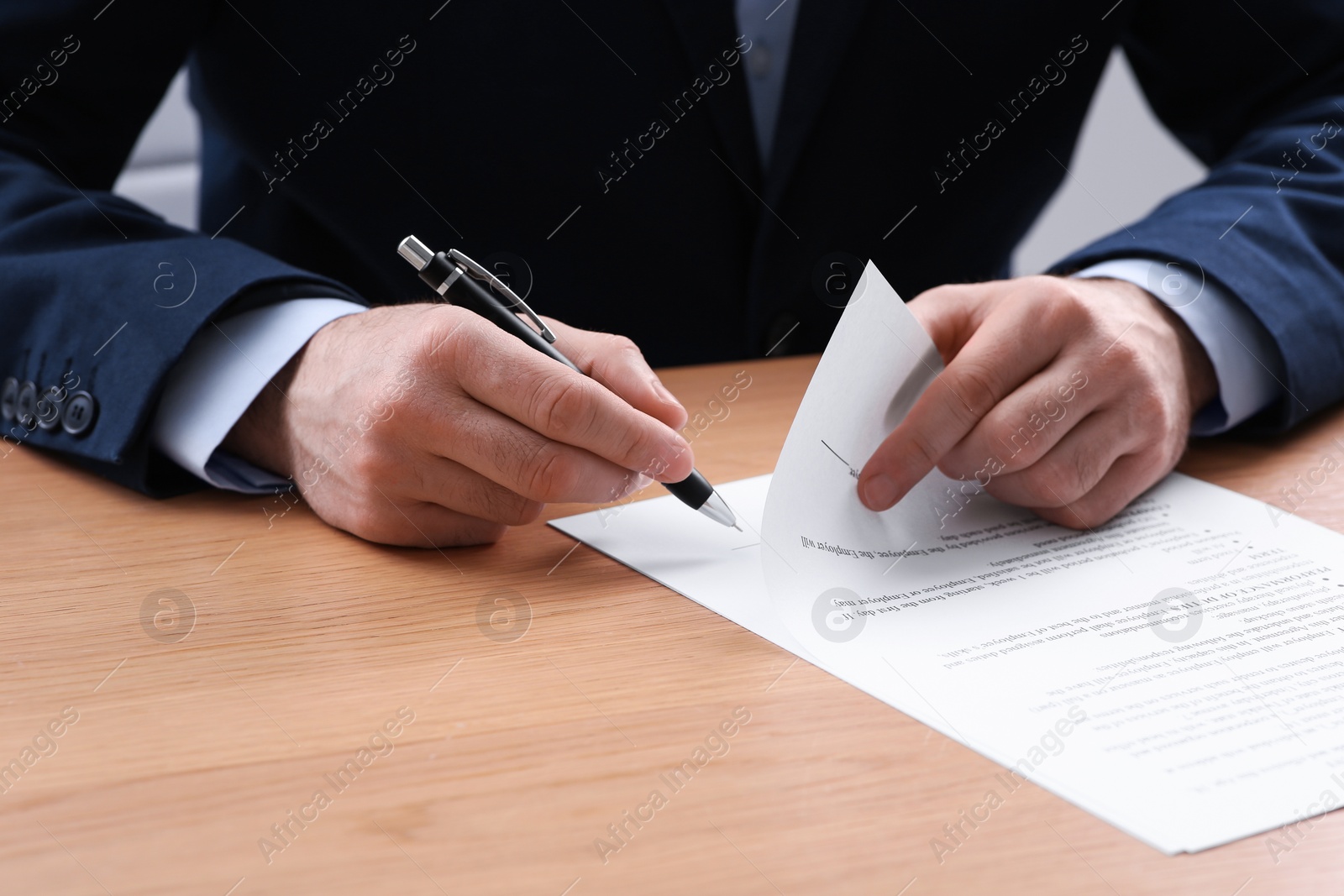 Photo of Businessman signing contract at wooden table, closeup of hands