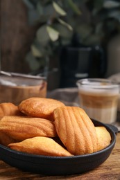 Photo of Delicious madeleine cakes in frying pan on wooden table, closeup. Space for text