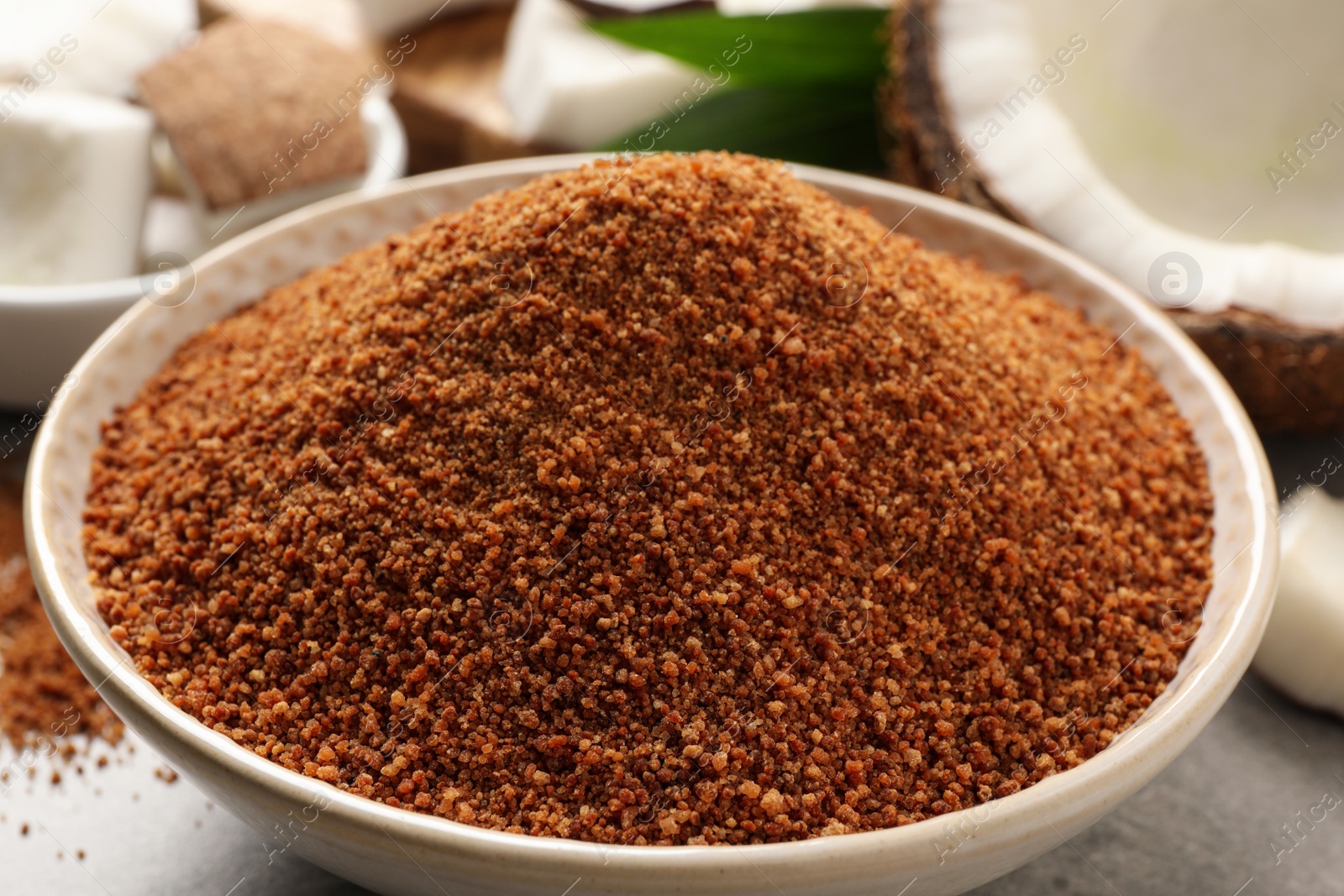 Photo of Natural coconut sugar in ceramic bowl on table, closeup