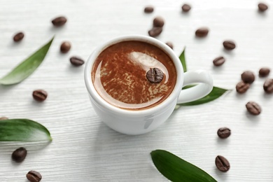 Cup of aromatic hot coffee and beans on wooden background