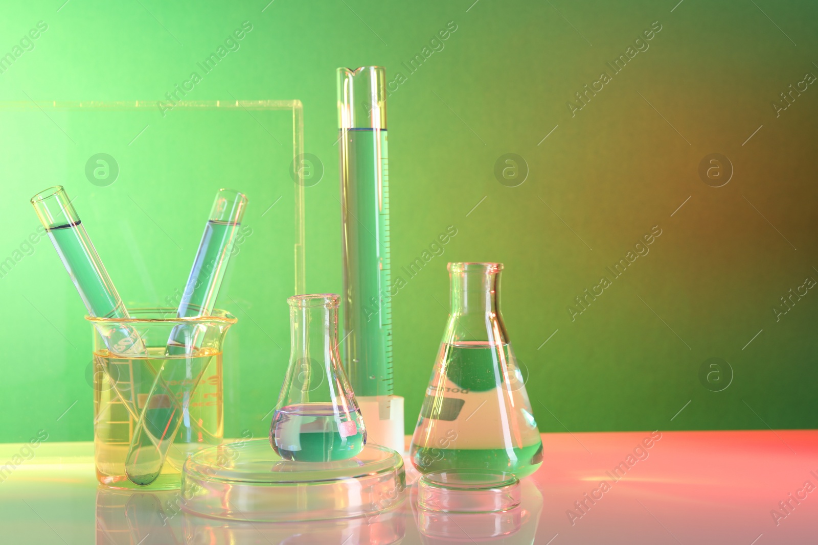 Photo of Laboratory analysis. Different glassware on table against color background, space for text