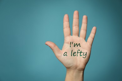 Image of Left-handed woman holding open palm on light blue background, closeup 