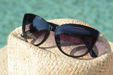 Photo of Stylish hat and sunglasses on blurred background, closeup