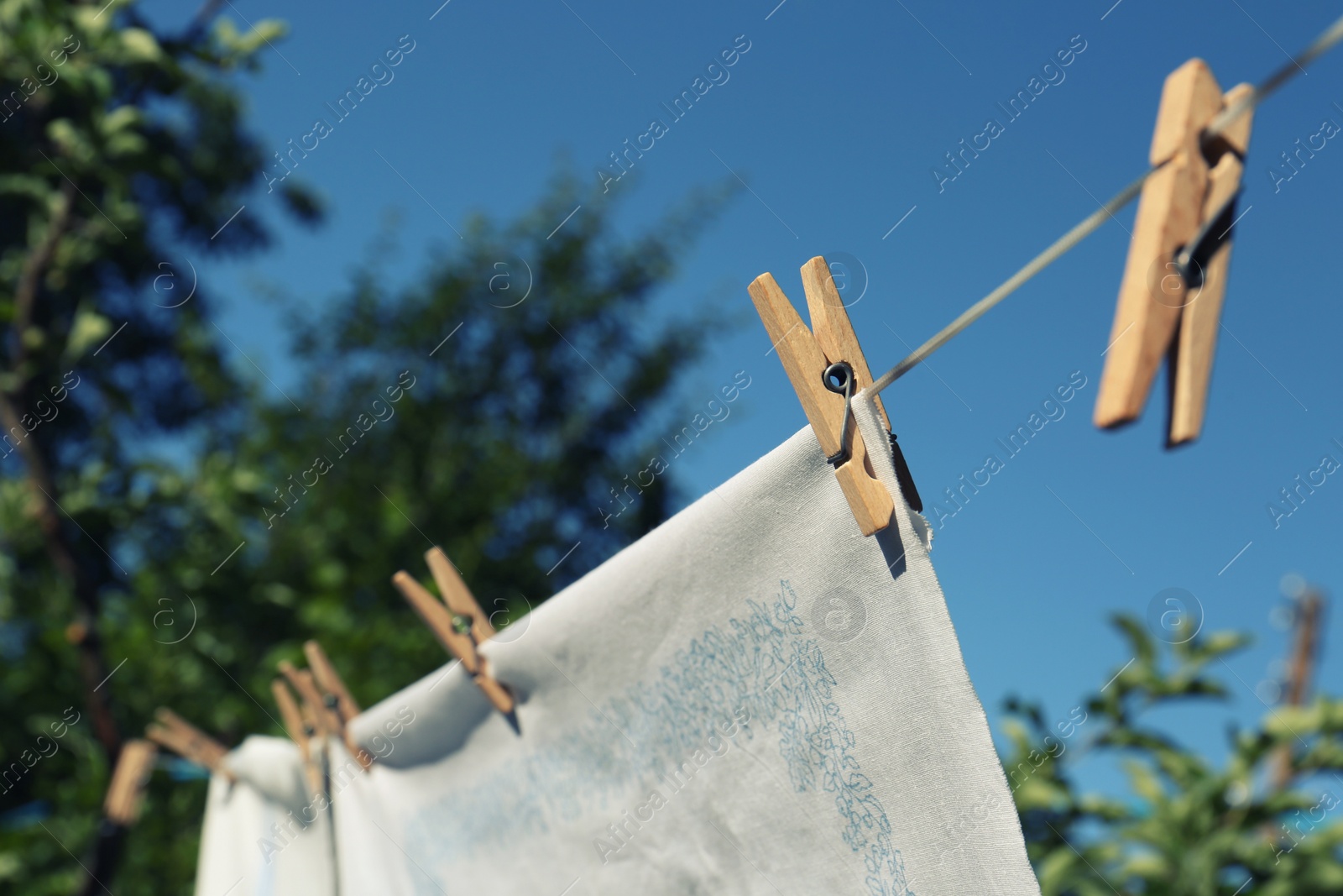 Photo of Washing line with clean laundry and clothespins outdoors, closeup