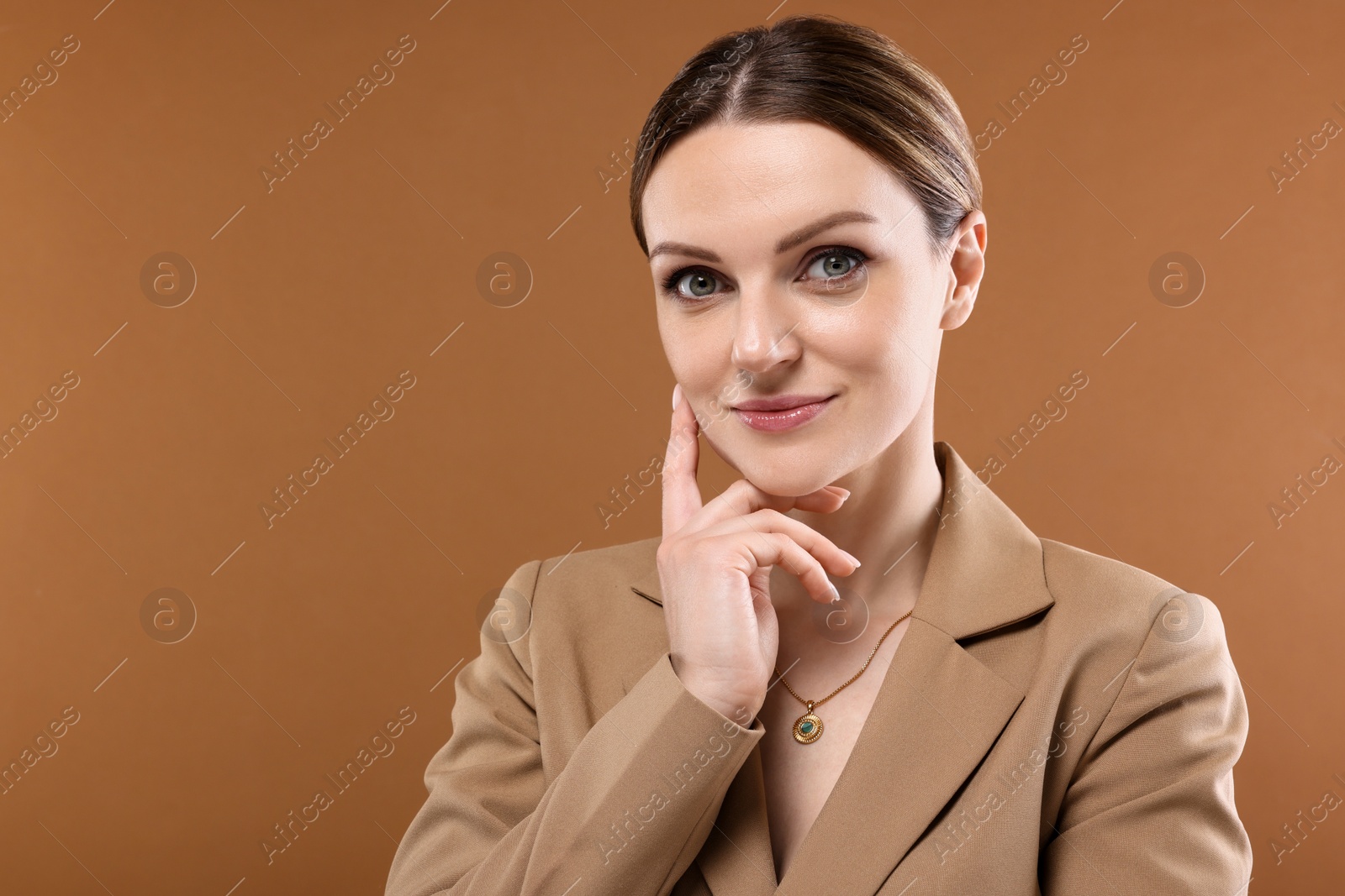 Photo of Beautiful woman with elegant necklace on brown background