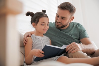 Little girl with father reading fairy tale in living room