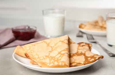 Photo of Folded fresh thin pancakes on light grey table