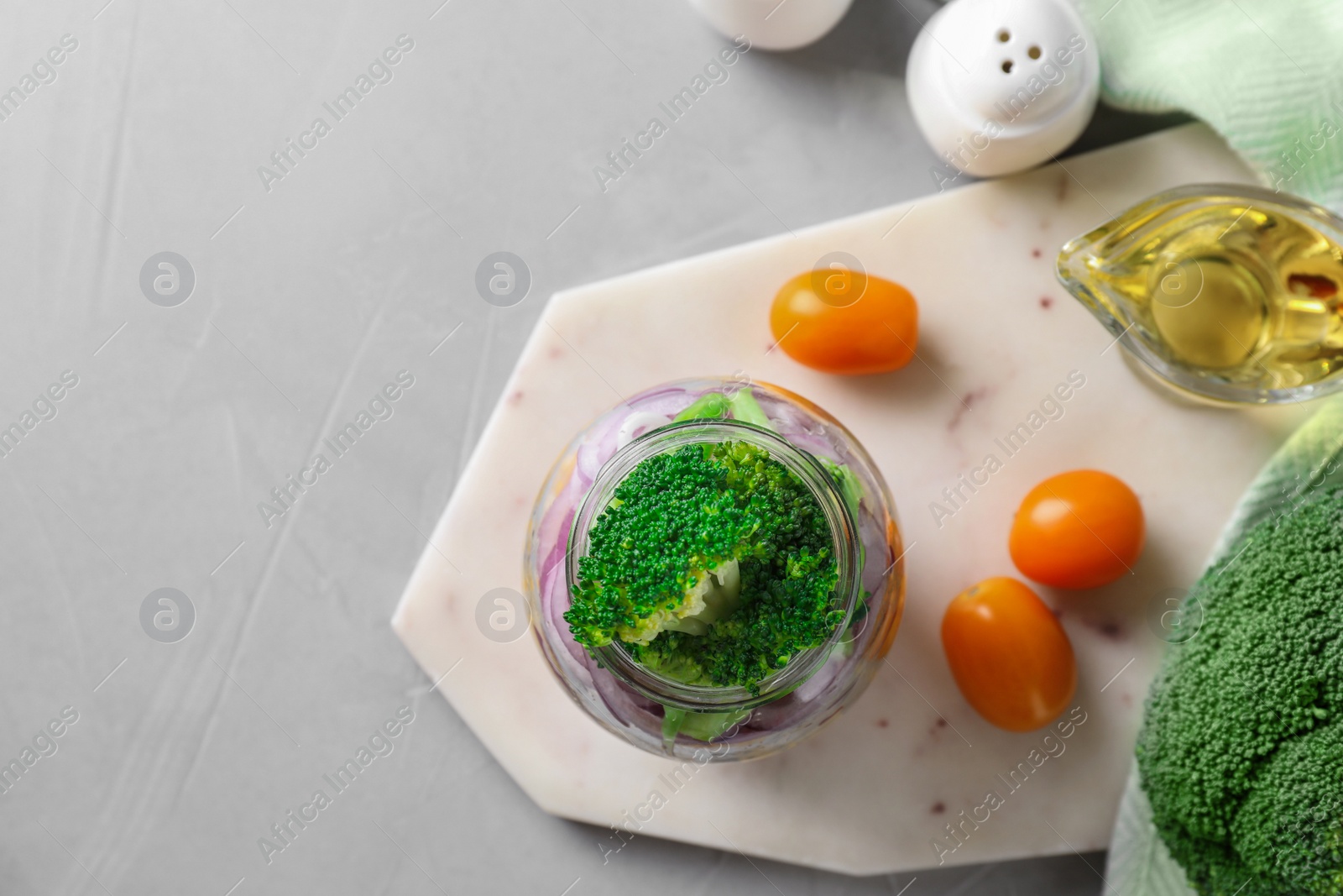 Photo of Healthy salad in glass jar on light grey table, flat lay. Space for text