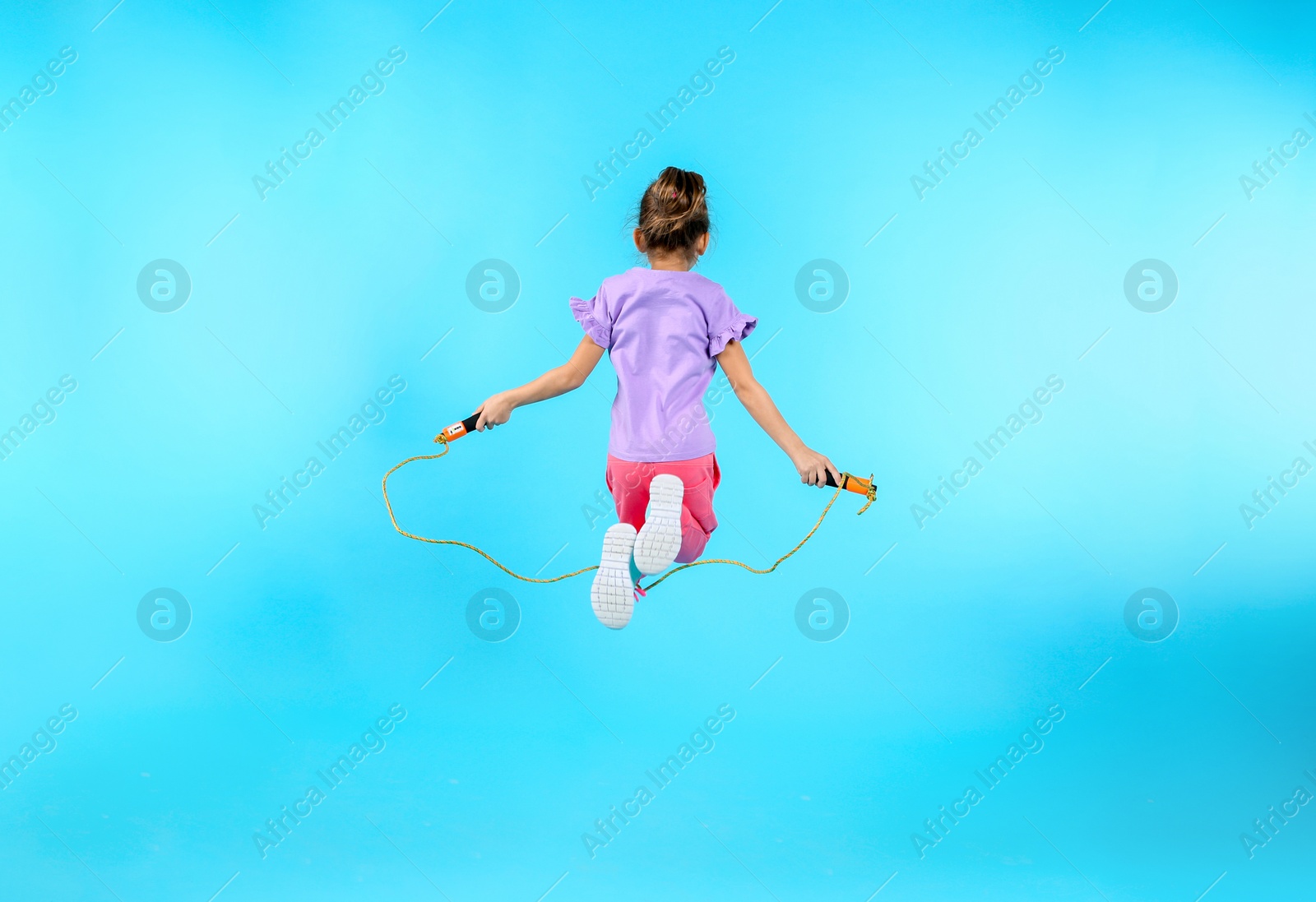 Photo of Active girl jumping rope on color background