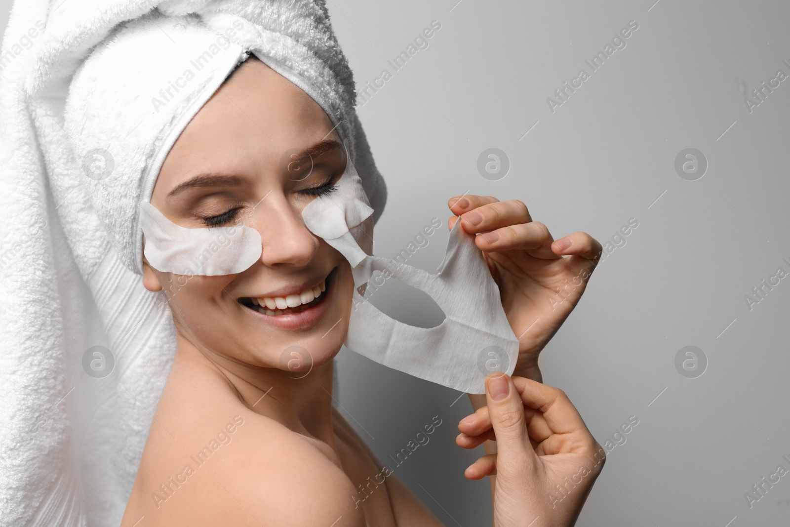 Photo of Beautiful woman with cotton face and eye masks against light background