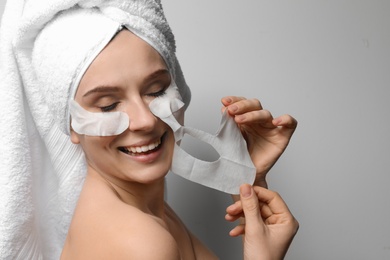 Photo of Beautiful woman with cotton face and eye masks against light background