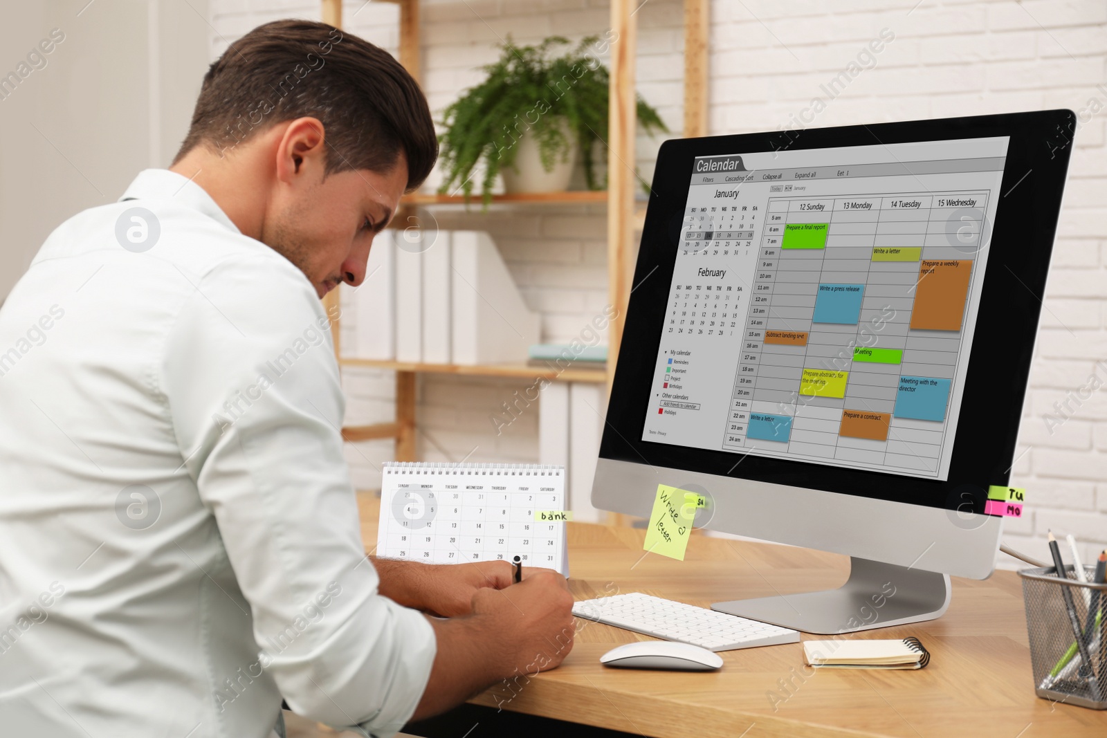 Photo of Man using calendar app on computer in office