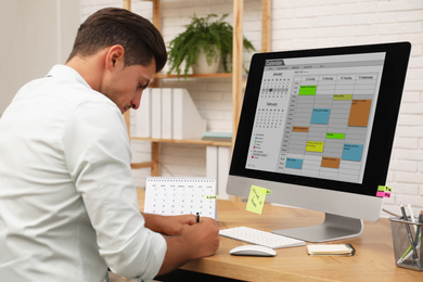 Man using calendar app on computer in office