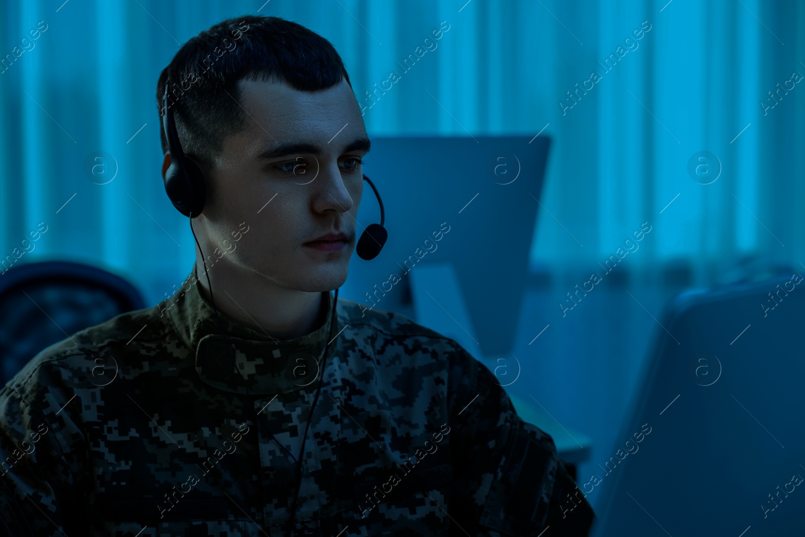 Image of Military service. Soldier in headphones working in office at night