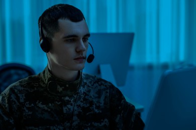 Military service. Soldier in headphones working in office at night