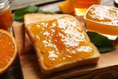 Photo of Delicious toasts with jam on wooden board, closeup