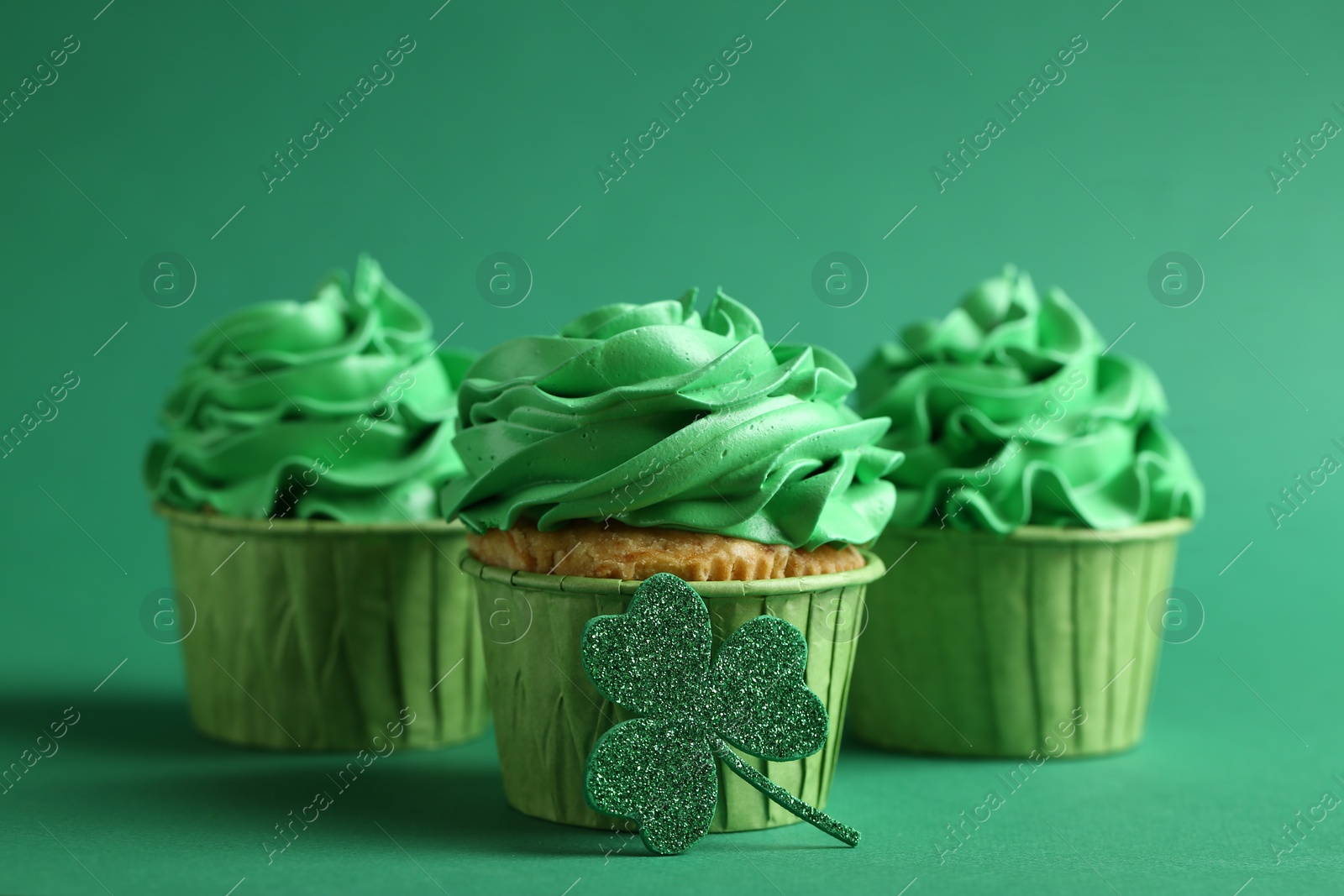 Photo of St. Patrick's day party. Tasty cupcakes on green background, closeup