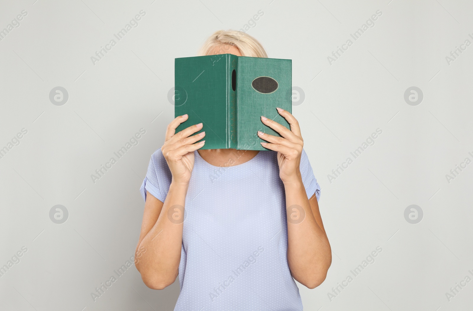 Photo of Mature woman reading book on light background