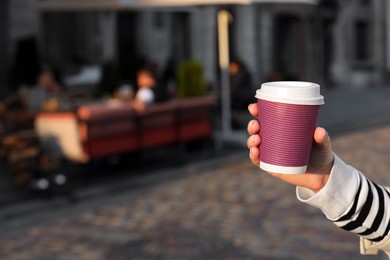 Photo of Woman holding paper takeaway cup on city street, closeup with space for text. Coffee to go