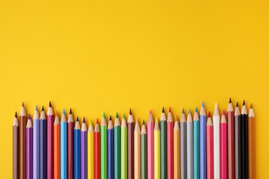 Photo of Colorful wooden pencils on yellow background, flat lay. Space for text