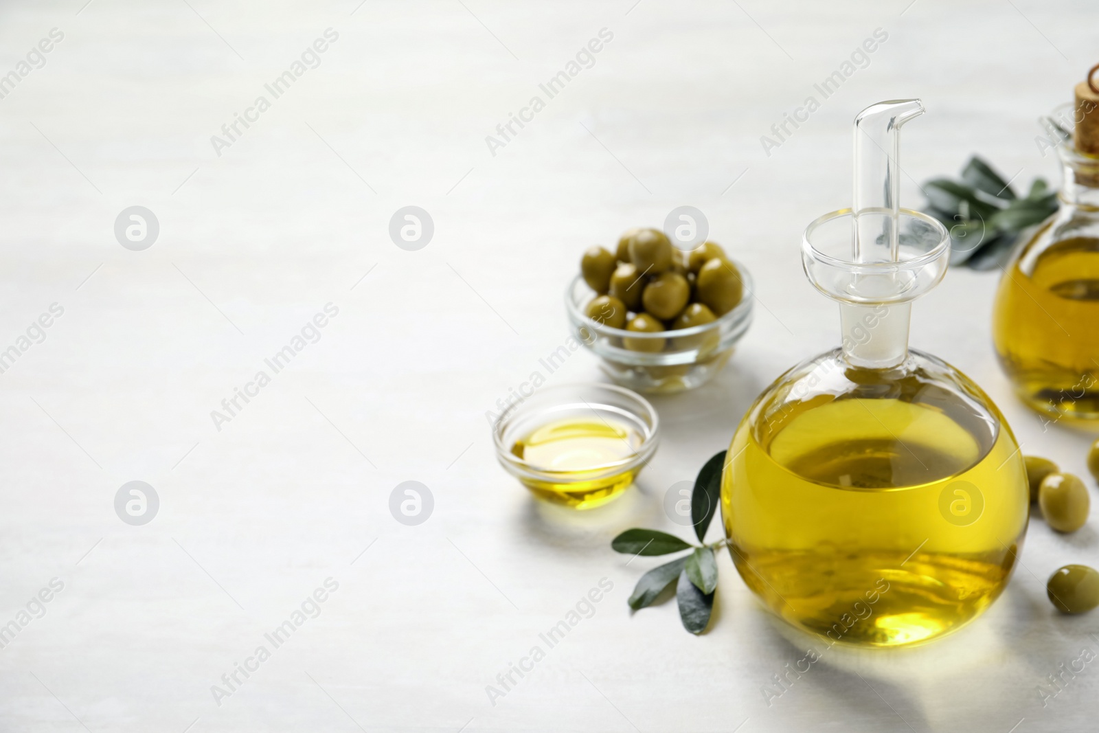 Photo of Bottle of fresh olive oil on white table, space for text