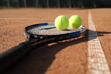 Photo of Tennis balls and racket on clay court, closeup