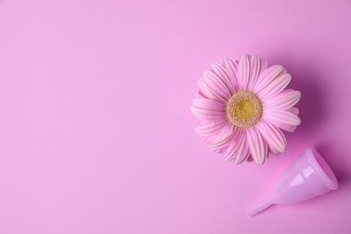 Flat lay composition with menstrual cup and gerbera flower on color background, space for text. Gynecological care