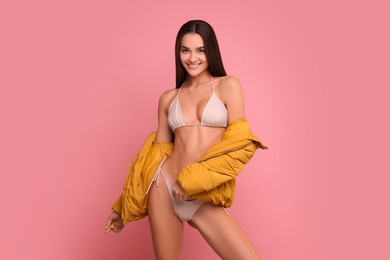 Young woman in stylish bikini and jacket on pink background