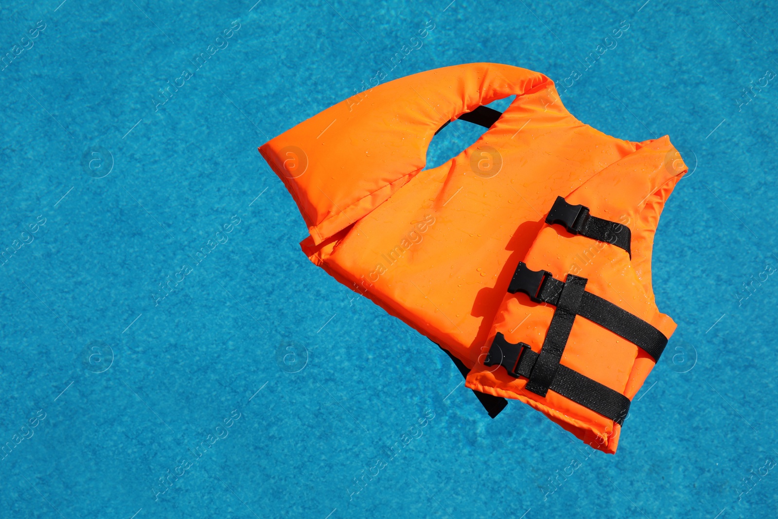 Photo of Bright orange life jacket floating in swimming pool