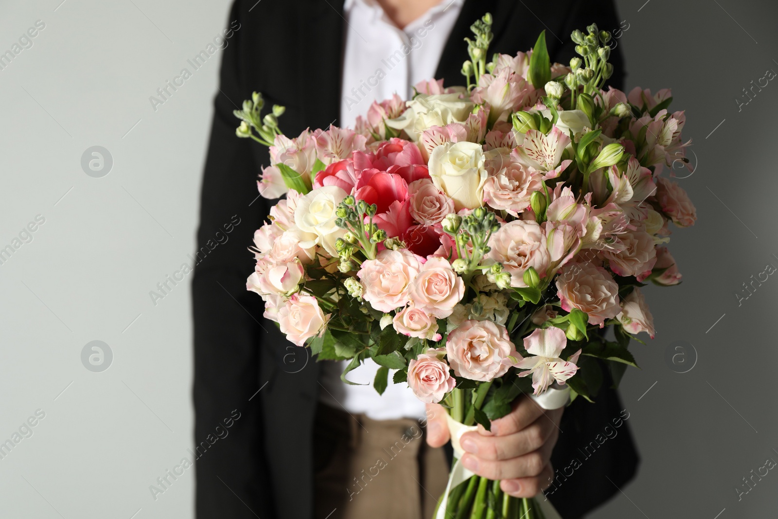 Photo of Man with beautiful bouquet of flowers on grey background, closeup