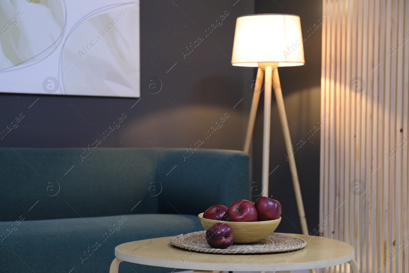 Photo of Red apples on wooden coffee table near sofa in room