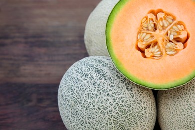 Photo of Whole and cut fresh ripe melons on wooden table, closeup. Space for text