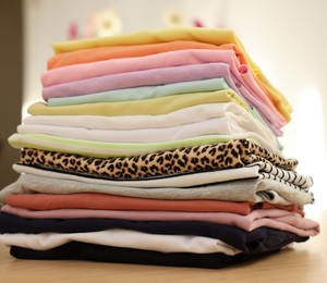 Photo of Stack of clean clothes on wooden table