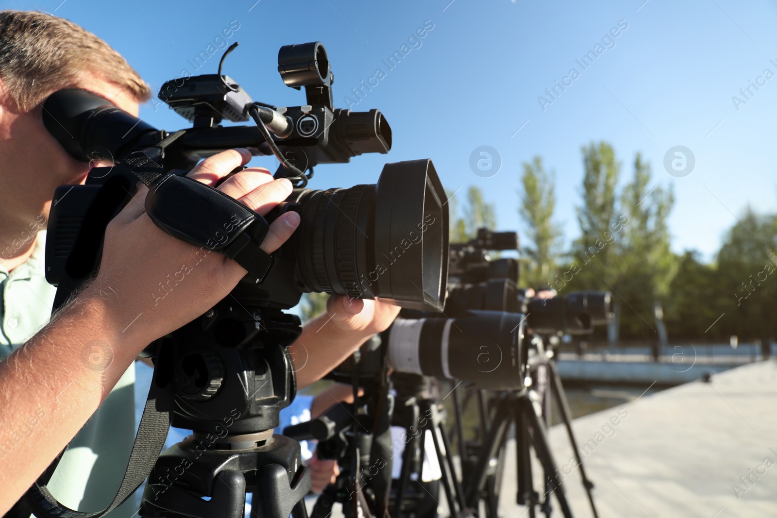 Photo of Operators with professional video cameras working outdoors on sunny day