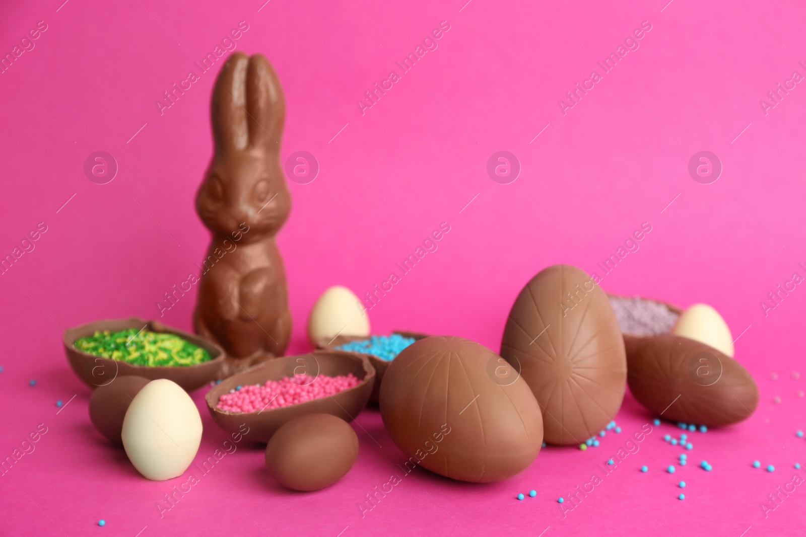 Photo of Sweet chocolate eggs and bunny on pink background