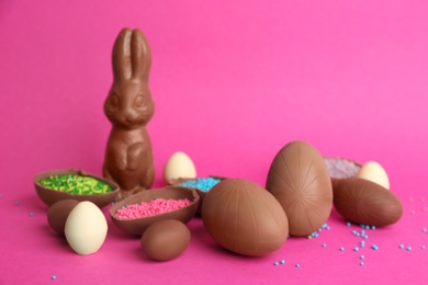 Photo of Sweet chocolate eggs and bunny on pink background