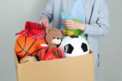 Photo of Woman with box of unwanted stuff on grey background, closeup