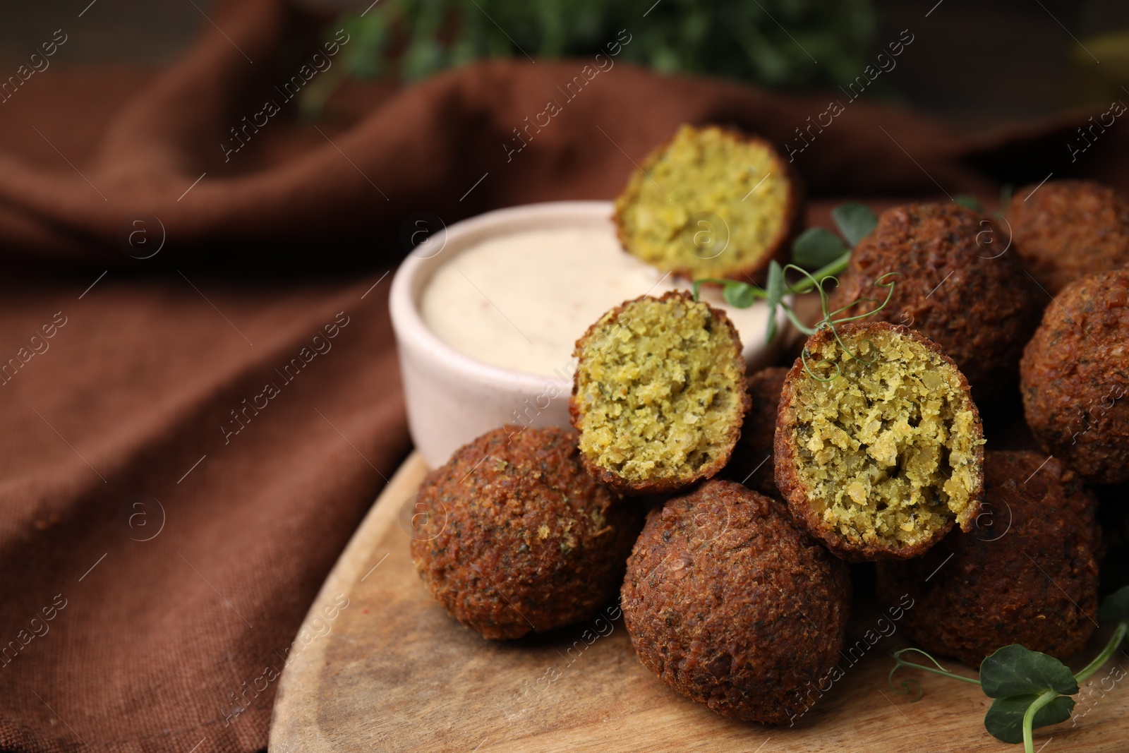 Photo of Delicious falafel balls and sauce on table, closeup