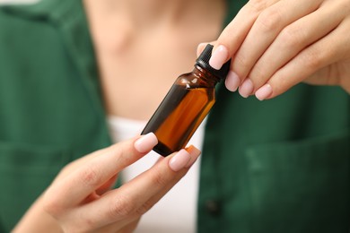 Aromatherapy. Woman with bottle of essential oil, closeup