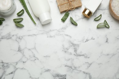 Flat lay composition with aloe vera and cosmetic products on white marble background. Space for text